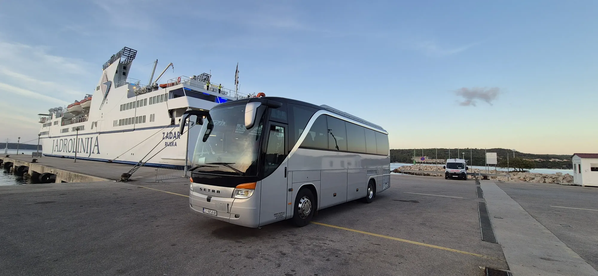 Group transfer coach at a ferry terminal quay with a ship behind on Hvar