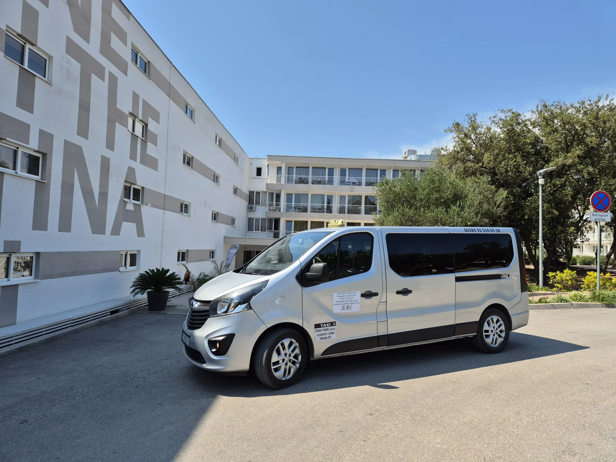 Silver passenger van taxi parked beside a large hotel on Hvar for guest transfers