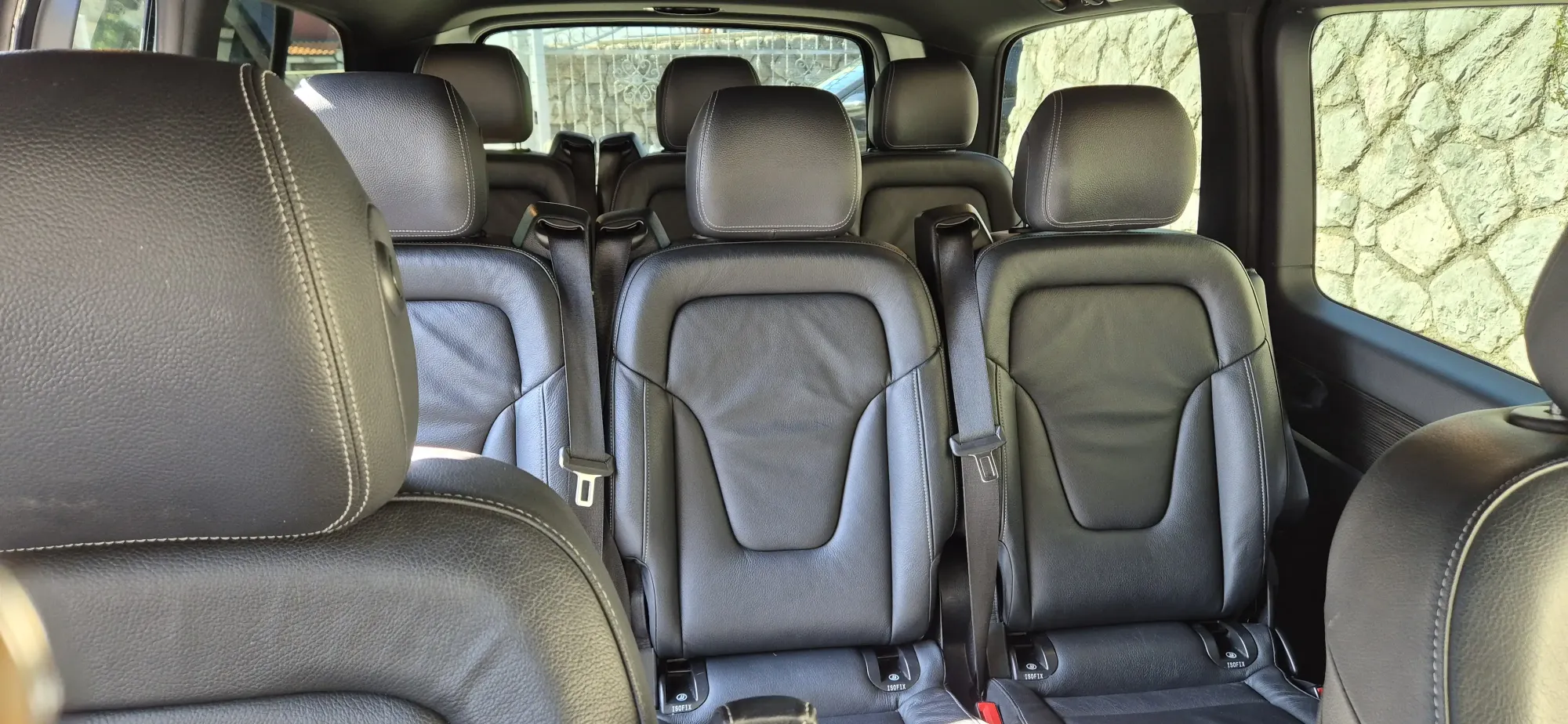 Spacious black leather passenger seats inside a luxury van for comfortable group transfers